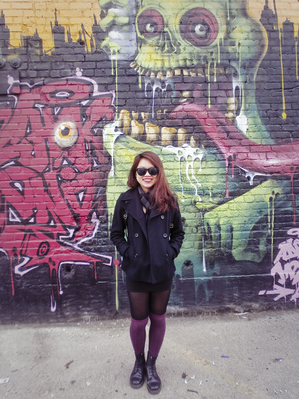 Jac in front of a wall of colourful murals.