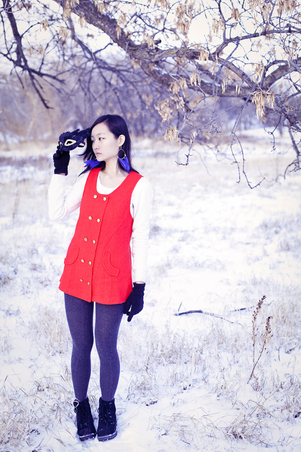 Self-portraiture photography in the snow- Feather masked red vest. Outfit details: gifted wool cape, thrifted red vest, Uniqlo cashmere sweater, River Island panda scarf, Forever21 knit tights, H&M blue feather hoop earrings, Fila boots. 