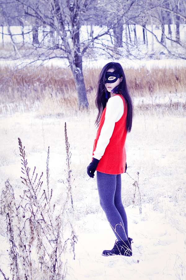 Self-portraiture photography in the snow- Feather masked red vest. Outfit details: gifted wool cape, thrifted red vest, Uniqlo cashmere sweater, River Island panda scarf, Forever21 knit tights, H&M blue feather hoop earrings, Fila boots. 