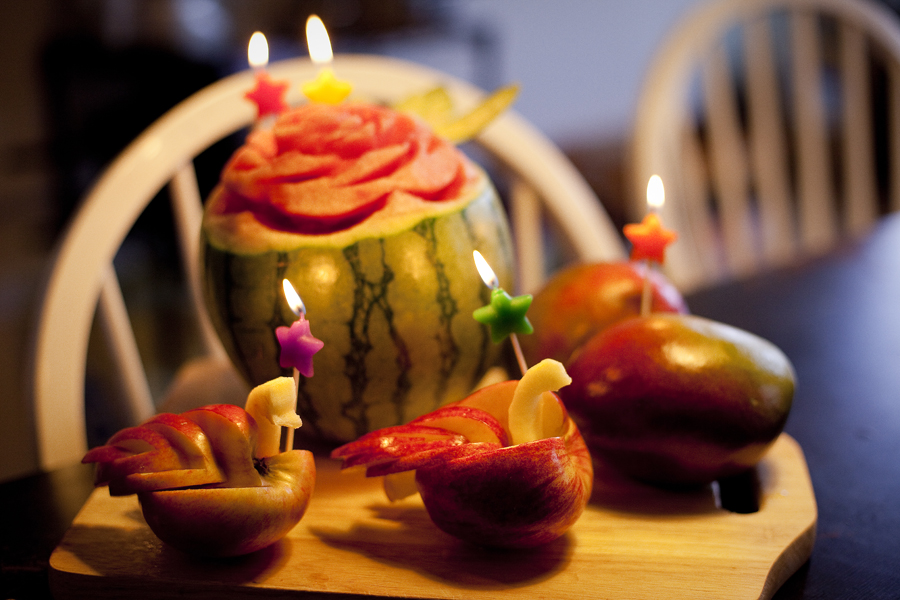 Candles on sculpted watermelon flower and swan apples.