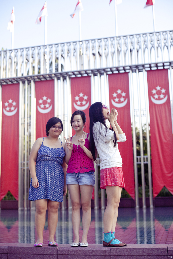 Puey, Ade, and Ren in front of Singapore flags.