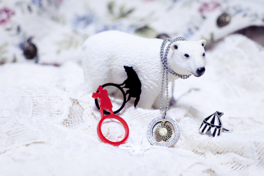 Closeup of accessories and my polar bear. Lickety Cut Red Riding Hood acrylic ring set, Redone Argentine coin necklace, white bunny ring, circus tent ring.