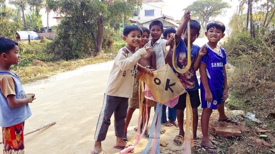 Locals kids holding up a snake and a kite outside the Lotus Lodge, Siem Reap, Cambodia.