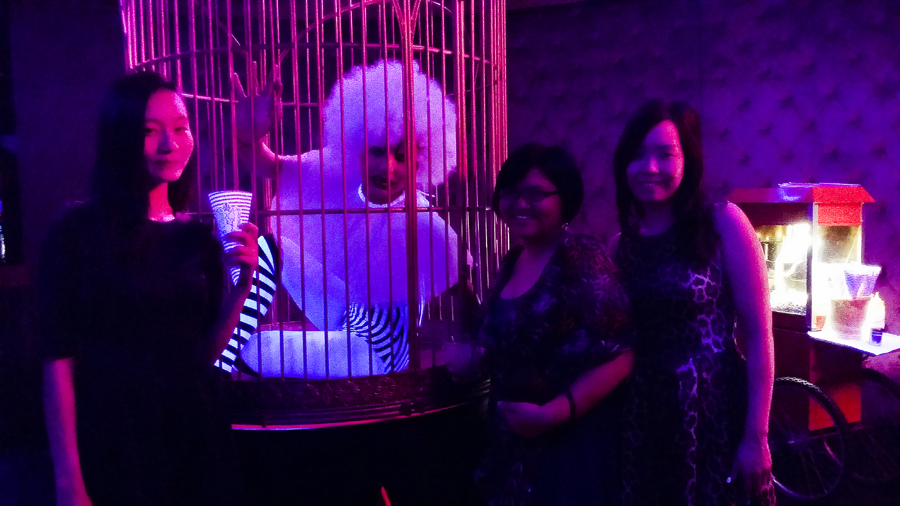 Ren, Puey, and Ade taking a picture with a performer in a cage at Cirque le Soir nightclub in Shanghai.