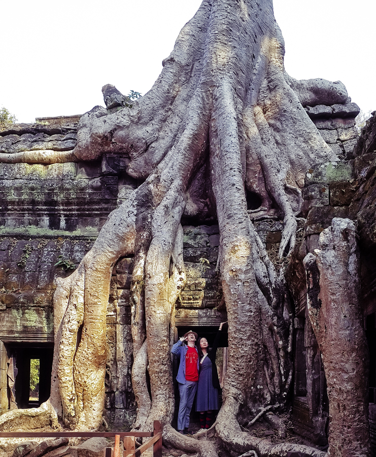 Ottie and Ren at a structure engulfed by a tree at Ta Prohm, Cambodia.
