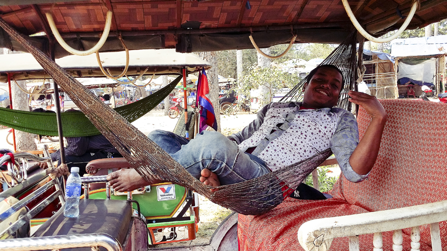 Tuk-tuk driver relaxing on a hammock in Cambodia.