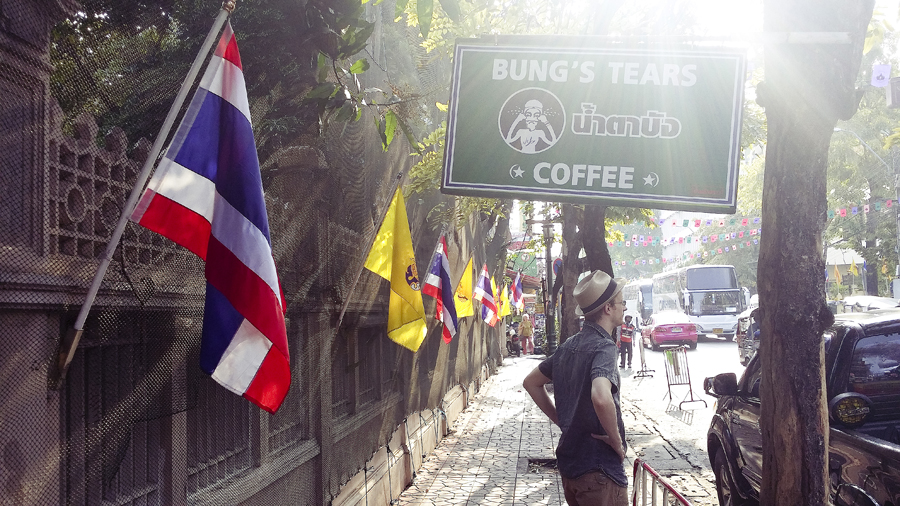 Ottie standing underneath a sign of Bung's Tears Coffee in Bangkok, Thailand.