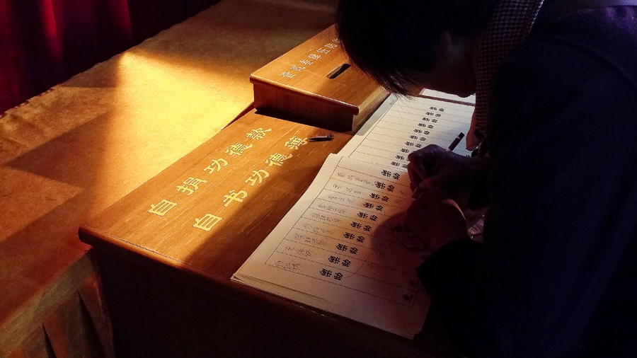 Writing down a name after donating to the temple at Jing'An temple, Shanghai.