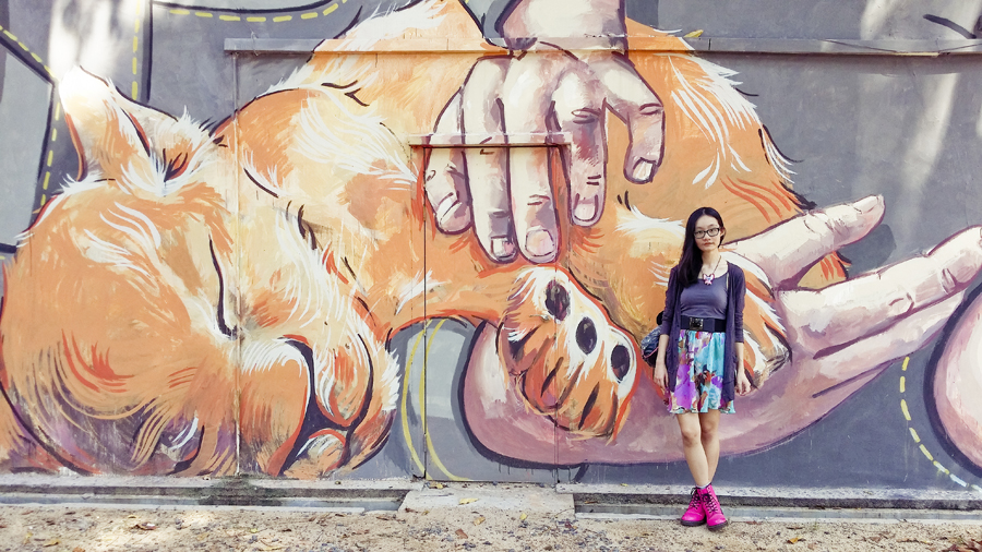 Ren posing with Girl and the Lion Cub, a mural by Ernest Zacharevic.