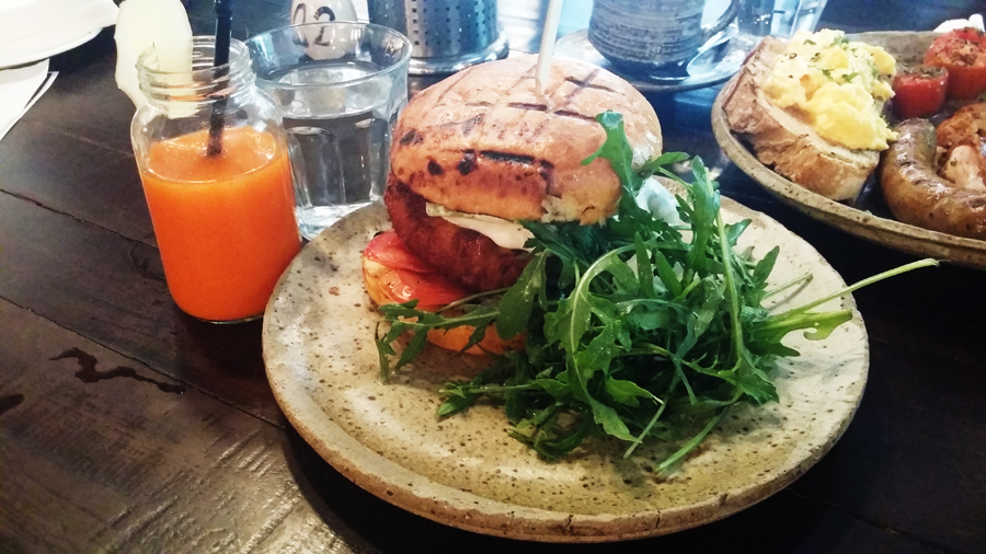 Fish Burger and a glass of Fresh orange, carrot & ginger juice from Common Man Coffee Roasters.