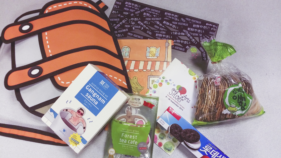 Orange 2D sling bag and korean snacks and tea and goodies on my desk.