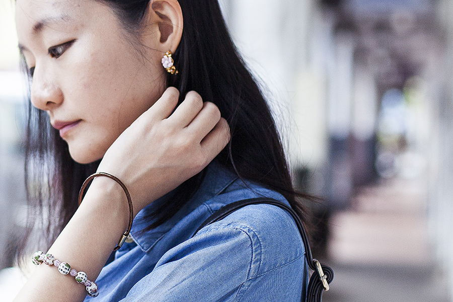 Closeup of gold floral hoop earring and chinese bead bracelet.