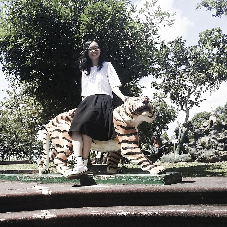 Ren sitting on a statue of a tiger at Haw Par Villa, Singapore.