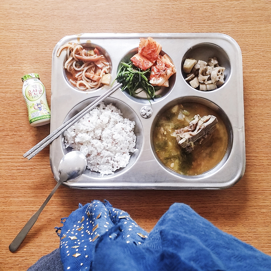 School lunch: probiotic drink, kimchi, lotus roots, pork ribs, spinach, steamed rice.