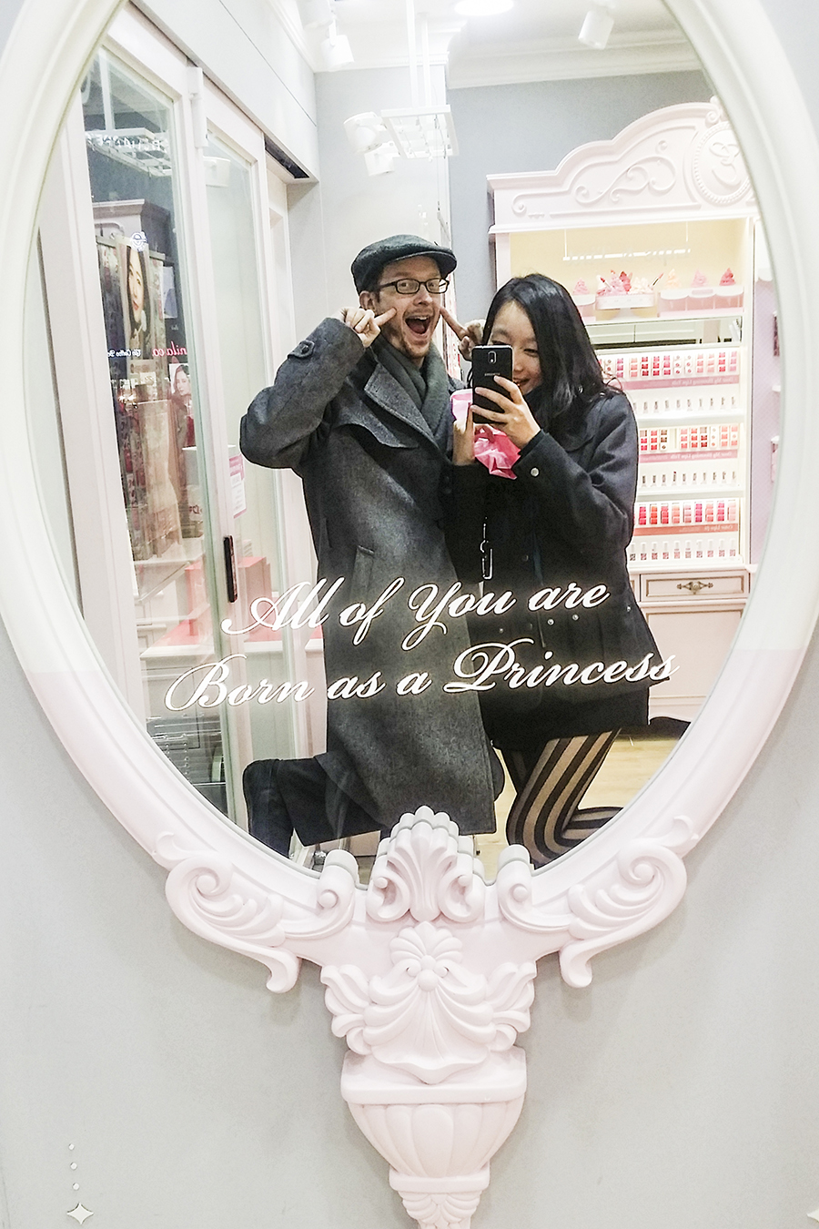 Ottie and Ren posing in front of a mirror at Etude House with the inscription: All of you are Born as a Princess, in Myeongdong, Seoul, South Korea.