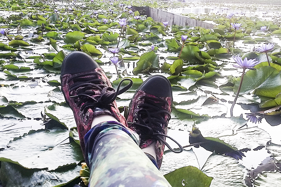 Red Rush Alexander McQueen sneakers and H&M abstract leggings against a lotus pond at Marina Bay Sands, Singapore.