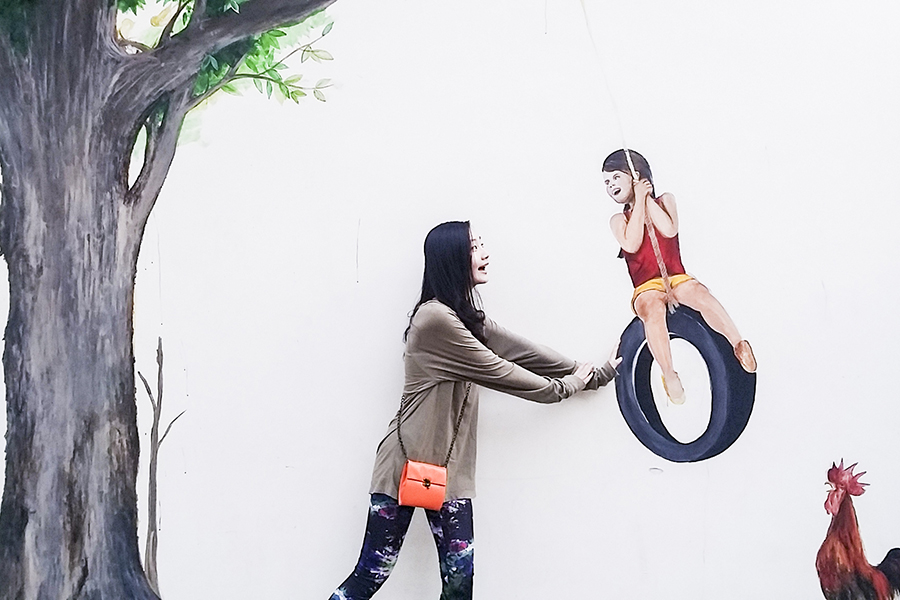 Ren pushing a girl on a tire swing illustrated mural in Singapore.