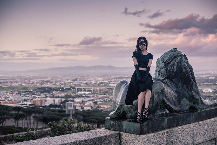 Sitting atop lion sculpture at Rhodes Memorial, Table Mountain National Park, Cape Town, South Africa.