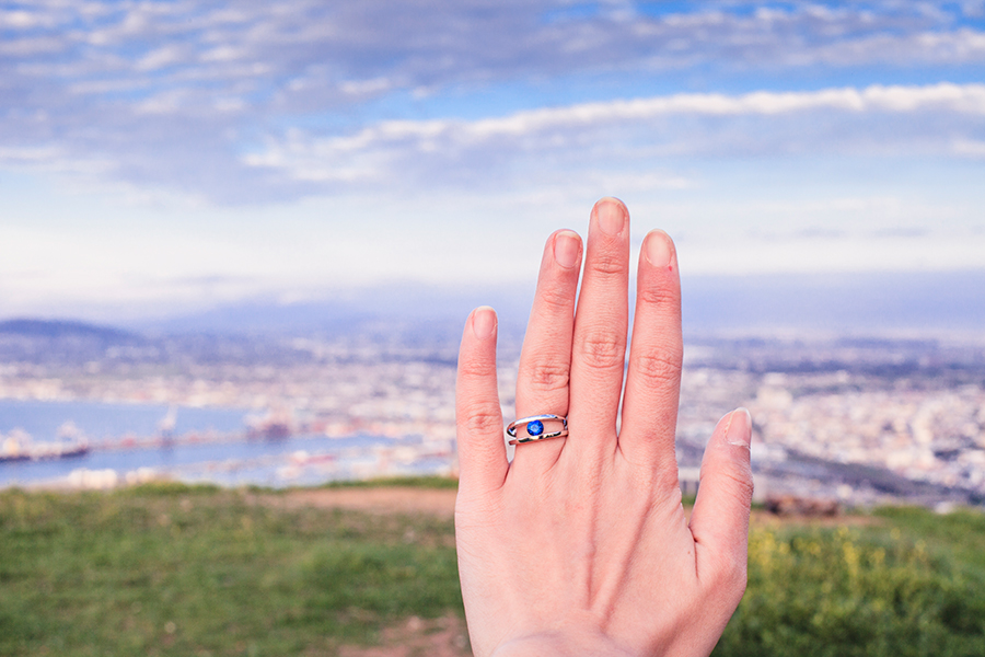 Sapphire gemstone set in platinum band engagement ring against the city of Cape Town, South Africa.