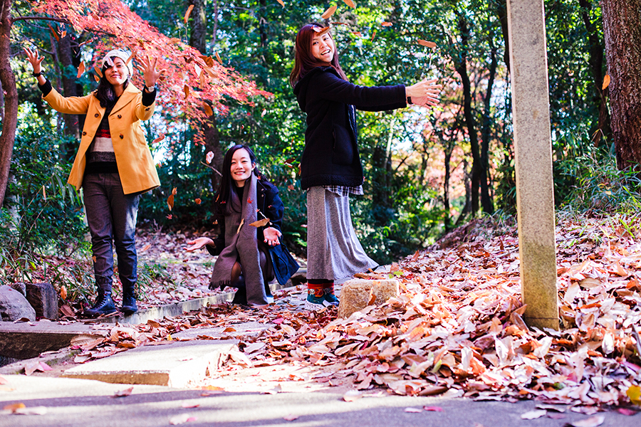 Shasha, Ren, and Ruru throwing dried maple leaves in the air.