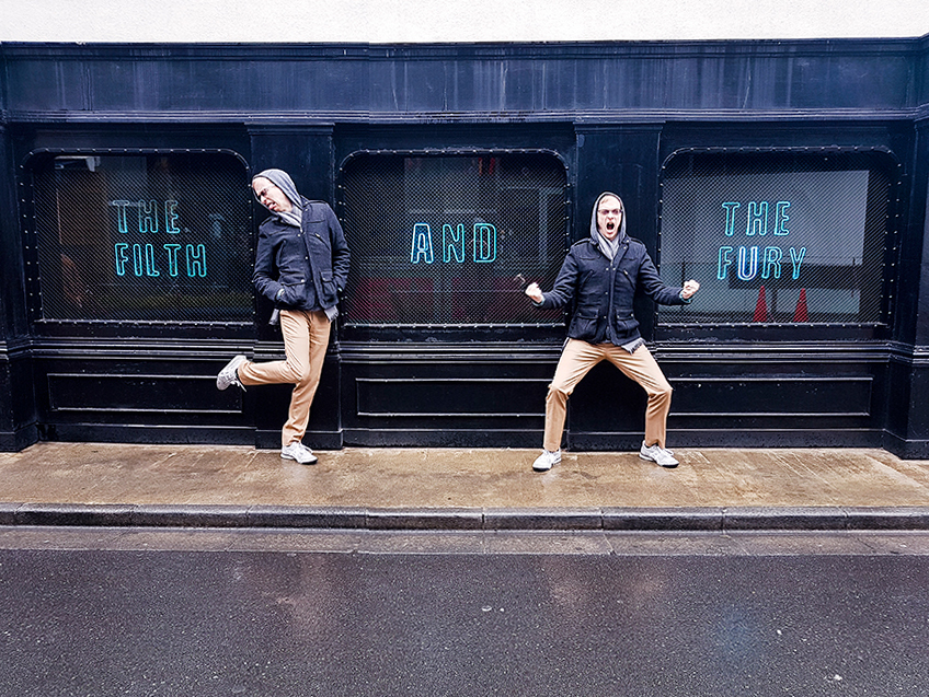 Ottie posing by signage of The Filth and The Fury, Tokyo.